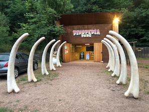 A building labeled 'DINOPEDIA PARC' with a sign, surrounded by large, curved structures resembling tusks.