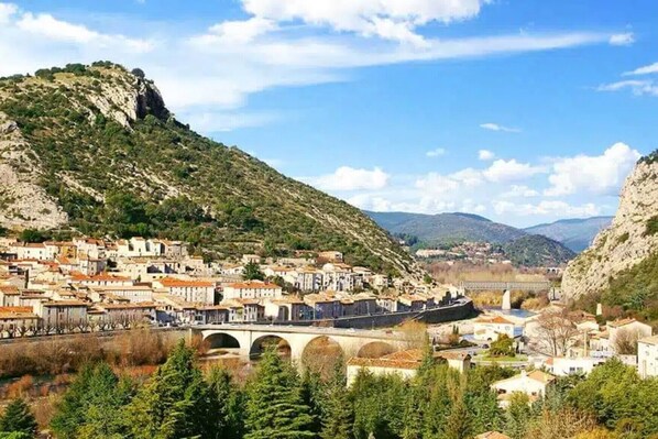 Une ville avec un pont, des bâtiments et un paysage montagneux en arrière-plan.