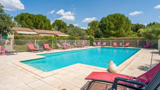 Ein rechteckiger Swimmingpool mit Liegestühlen und einer gefliesten Poolterrasse.