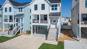 Uma fileira de casas de praia de dois andares com varandas, um alpendre e um pequeno jardim frontal.