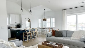 Uma sala de estar moderna com um sofá cinza, uma mesa de centro e uma área de jantar com mesa e cadeiras.