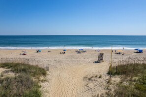 A beach with clear skies, sandy shore, and several umbrellas and beach chairs.