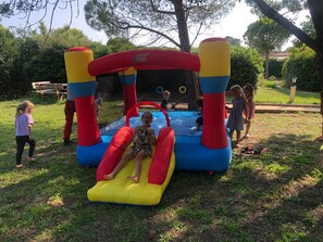 Un château gonflable avec un toboggan et une petite piscine.
