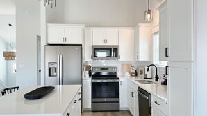 A modern kitchen with white cabinetry, stainless steel appliances, and a central island. - Walk To The Beach! Pet Friendly! (Kill Devil Hills)
