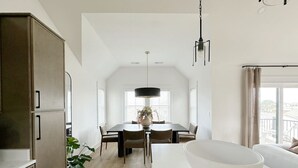 A modern kitchen with a dining area, a large white bowl on the counter, and a potted plant. - Cocoa Beach! Luxury Pet Friendly Beach Home! (Kill Devil Hills)