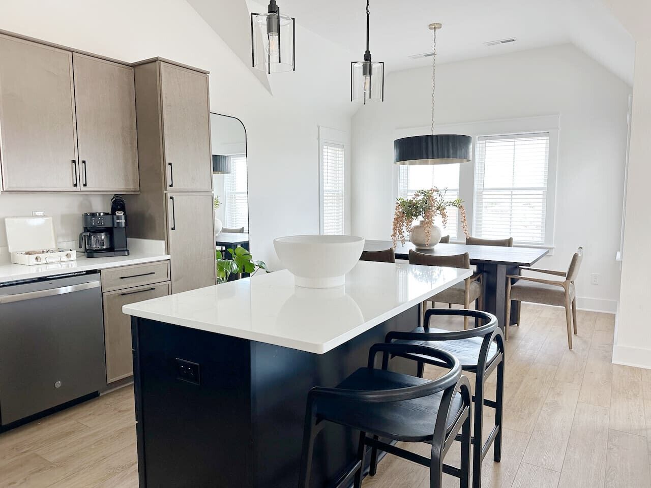 A modern kitchen with a central island, stainless steel appliances, and a dining area with a large window.