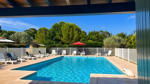 A swimming pool with lounge chairs and a covered area.