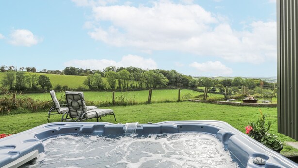 A hot tub with a view of a green field and trees. - Brondel Luxury Shepherd's Hut (Aberystwyth)