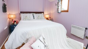 A bedroom with a bed, two bedside tables with lamps, a window with curtains, a radiator, and a wall-mounted coat hook. - Brondel Luxury Shepherd's Hut (Aberystwyth)