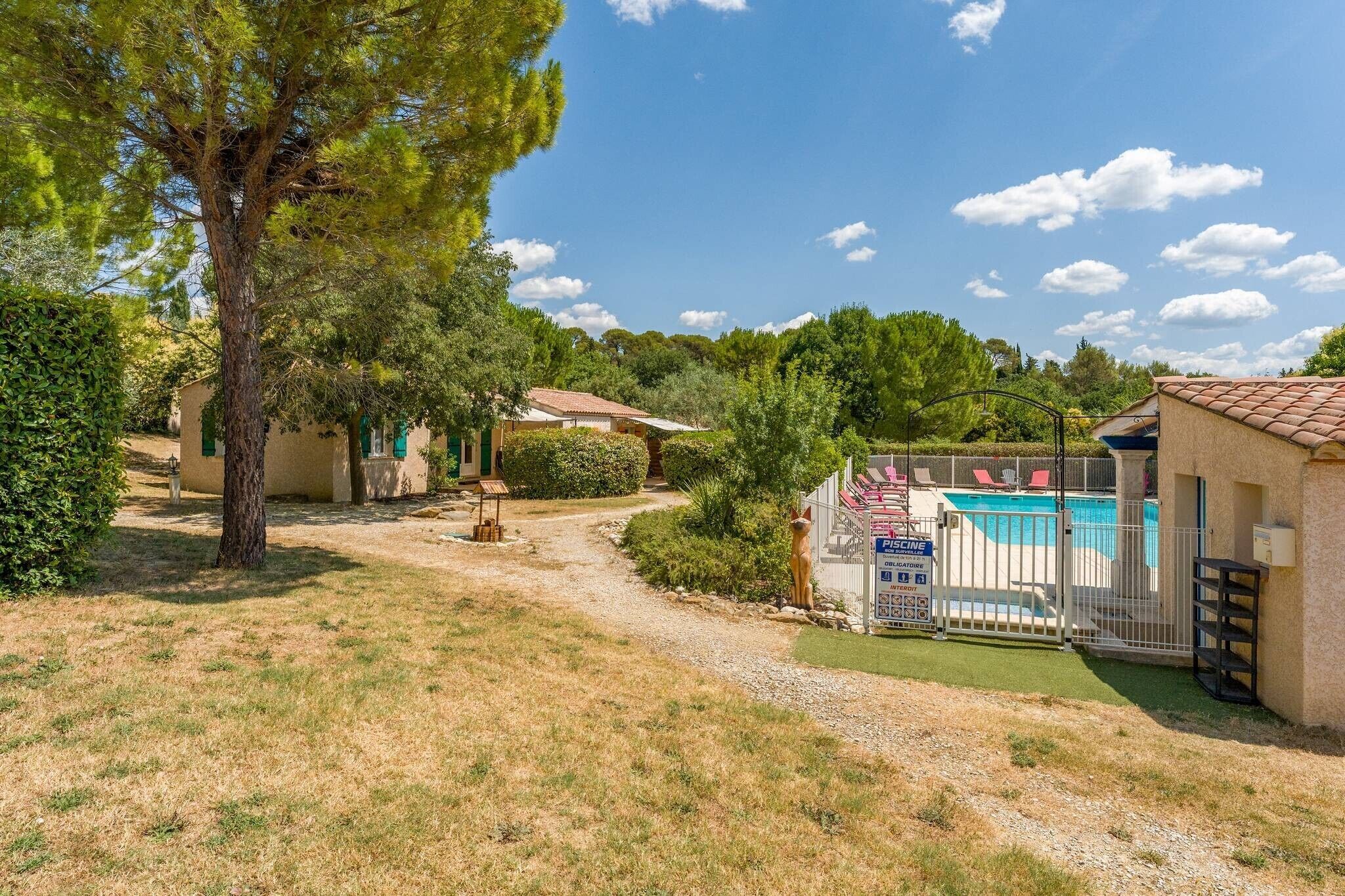 Una propiedad residencial con piscina, camino de acceso pavimentado y césped bien cuidado.