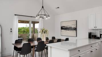 A modern kitchen with white cabinets, a large island, and a dining area with a table and chairs.