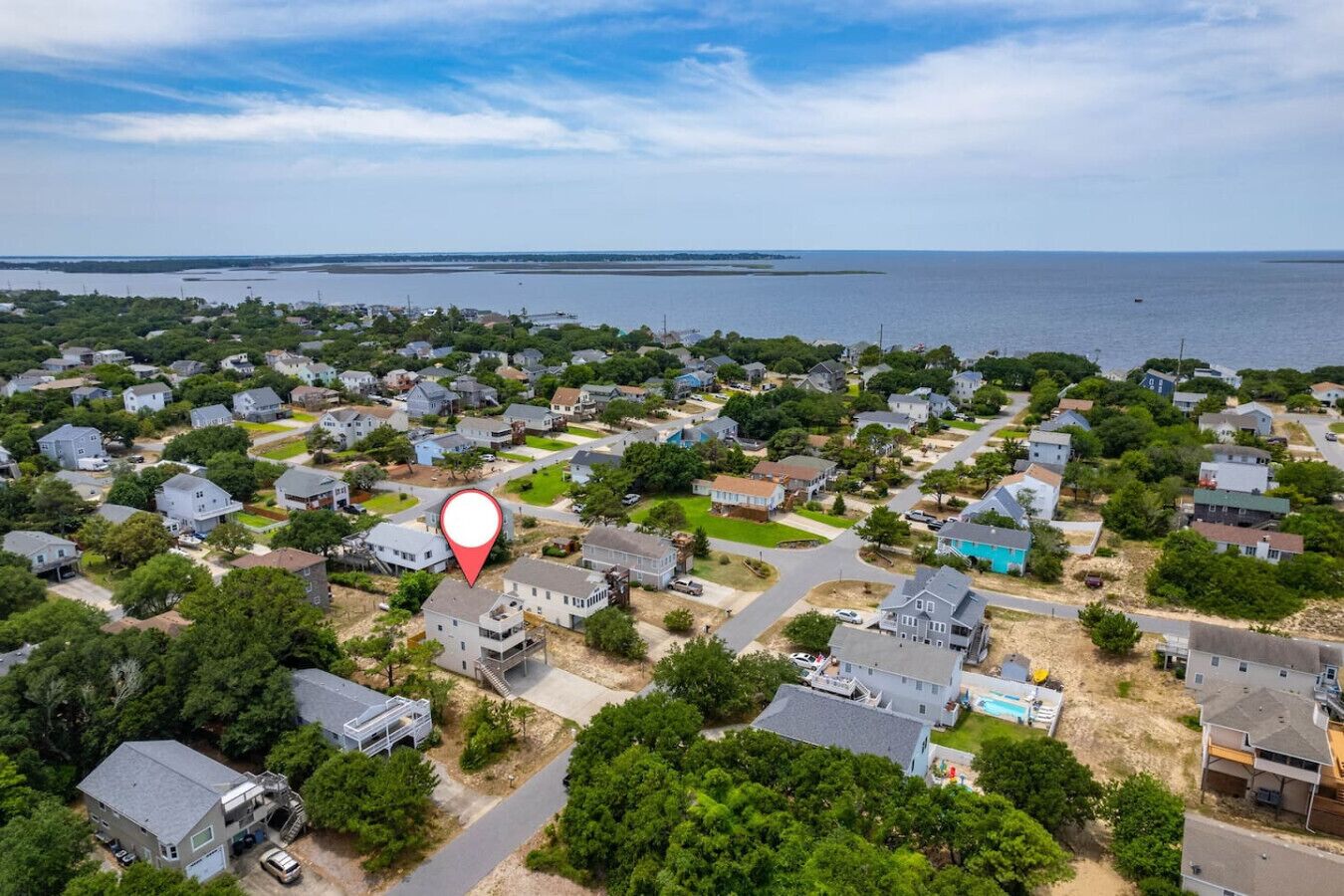 An aerial view of a residential area with houses, roads, and a body of water in the background.