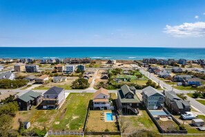 A coastal residential area with houses, a swimming pool, and a beach in the background. - Ocean Views, Pet Friendly, Pool, Walk To Beach! (Nags Head)