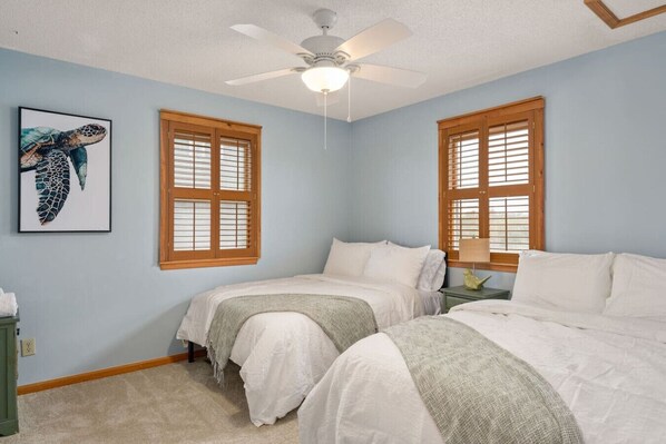 A bedroom with two beds, a ceiling fan, and a framed artwork on the wall. - Ocean Views, Pet Friendly, Pool, Walk To Beach! (Nags Head)