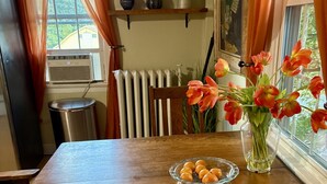 Ett matbord i trä med en glasskål full av apelsiner, en vas med tulpaner och ett element i bakgrunden.