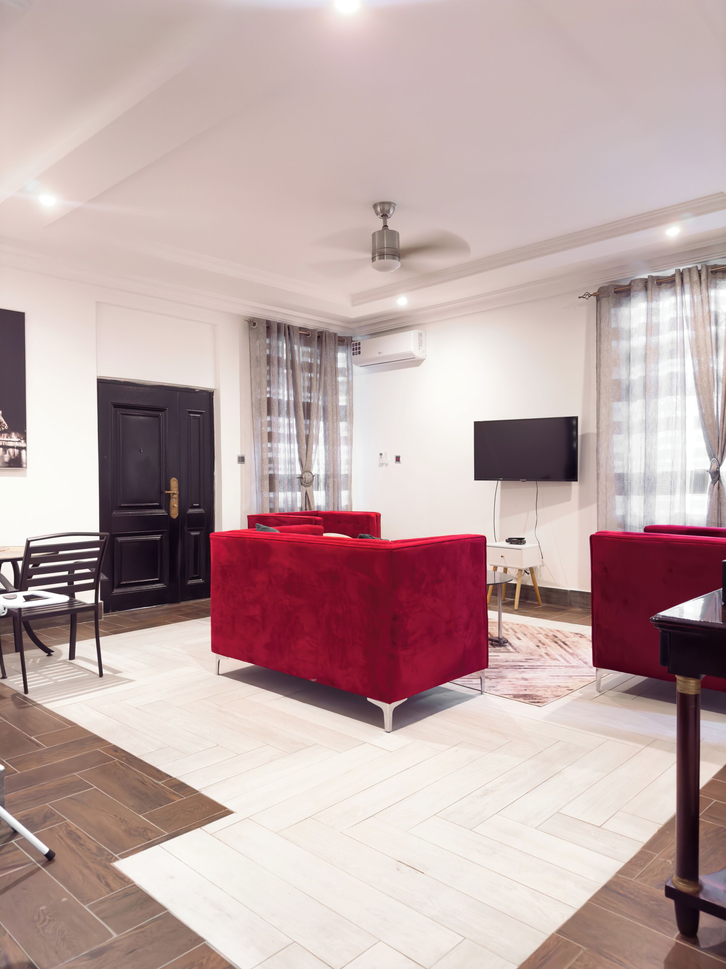 Een moderne woonkamer met een rode bank, een flatscreen-tv en een plafondventilator.