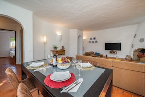 Ein Essbereich mit einem Tisch für vier Personen, einer Couch, einem Fernseher und einem Kamin.