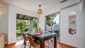 A dining area with a glass table, brown chairs, and a view of the outdoors. - Holiday Home 'Valentina' with Shared Pool, Wi-Fi and Air Conditioning (Carvoeiro)