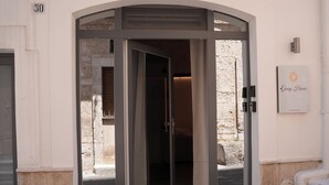 A hotel entrance with a glass door, a stone wall, and a sign that reads "Gusy House". - Giusy House (Ostuni)
