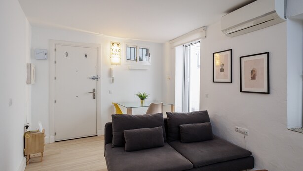 A modern living room with a sofa, a small table, a plant, and framed pictures on the wall.