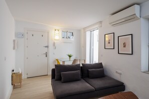 Uma sala de estar moderna com um sofá, uma mesinha, uma planta e quadros nas paredes.
