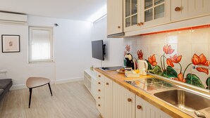 A kitchen with wooden cabinets, a built-in oven, a sink, and a window with blinds.