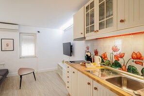 A kitchen with wooden cabinets, a built-in oven, a sink, and a window with blinds.