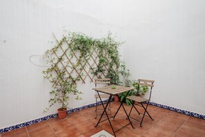 Une terrasse avec une table et des chaises en bois, une plante grimpante et une plante en pot.