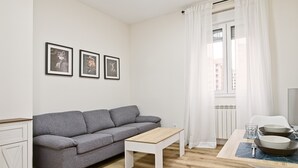 A modern living room with a grey sofa, a white coffee table, and a dining area with a table set for two. - Legio Suites N Apartment in León: 2 Bedrooms, Step-Free Access, Family Amenities (León)