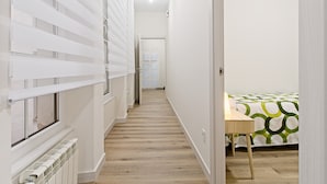 A narrow hallway with a radiator, a door at the end, and a bed with a green and white patterned bedspread. - Legio Suites N Apartment in León: 2 Bedrooms, Step-Free Access, Family Amenities (León)