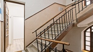 En trappe med trægelænder og metalspind, der fører til en platform med en dør markeret 'S'.