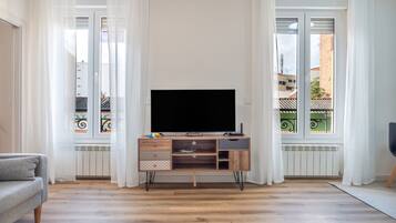 Ein Wohnzimmer mit einer Holz-Unterhaltungsanlage, einem Flachbildfernseher und einem grauen Sofa.