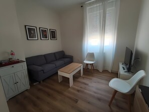 A living room with a sofa, a coffee table, a TV, a chair, and a cabinet.