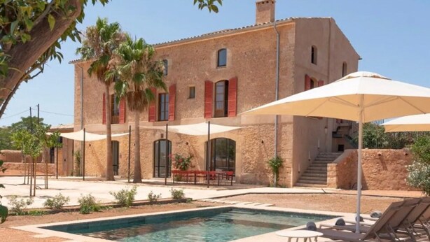 A two-story building with a swimming pool, outdoor seating, and palm trees. - S' Hort de ca'n salvà (Santa Maria del Camí)