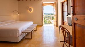A bedroom with a bed, bedside table, lamp, and a view through an open door. - S' Hort de ca'n salvà (Santa Maria del Camí)