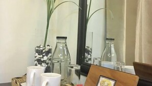 A room with a mirror, two white mugs, a glass bottle, and a decorative vase with stones. - Bohol Casa Nino Alona Resort (Panglao)