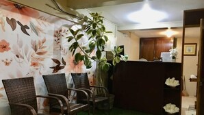A reception area with wicker chairs, a potted plant, and a floral wall. - Bohol Casa Nino Alona Resort (Panglao)