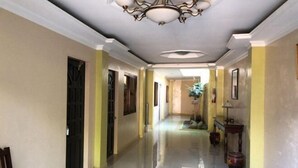 A hallway with a chandelier, doors, and a bench. - Bohol Casa Nino Alona Resort (Panglao)