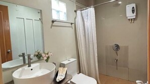Une salle de bain équipée d’un lavabo, de toilettes, d’une douche et d’un sèche-mains.