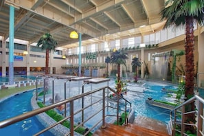 An indoor pool area with multiple water features, palm trees, and a visible 'ACE' sign. - Ace Suites by the WaterSpa - Budget Family Room (United St Pasig)