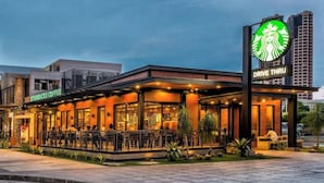 Un Starbucks Coffee tipo ventanilla con terraza y fachada de edificio moderna.