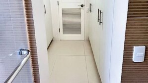 Un pasillo estrecho con una puerta al final, una barandilla a la izquierda y un interruptor de luz en la pared.