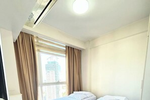 Une chambre d’hôtel avec un lit, une fenêtre avec des rideaux et un luminaire au plafond.