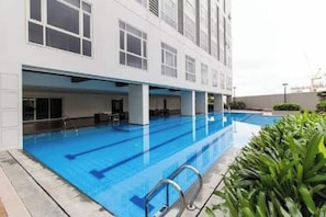 A modern building with a swimming pool, large windows, and a covered area with seating.