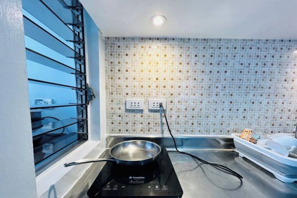 Una cocina con estufa, una ventana con persianas y un salpicadero de azulejos.