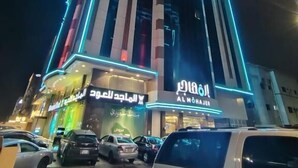 A modern building with illuminated signage, including 'ALMOHAJER' and 'ALMOHAJER' in Arabic. - ALMOHAJER SERVICED APARTMENTS (Jeddah)