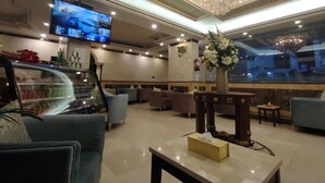 A hotel lobby with a large chandelier, a television mounted on the wall, and seating areas. - ALMOHAJER SERVICED APARTMENTS (Jeddah)