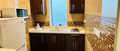 Een mini-koelkast, een kookplaat, kookgerei, borden en bestek