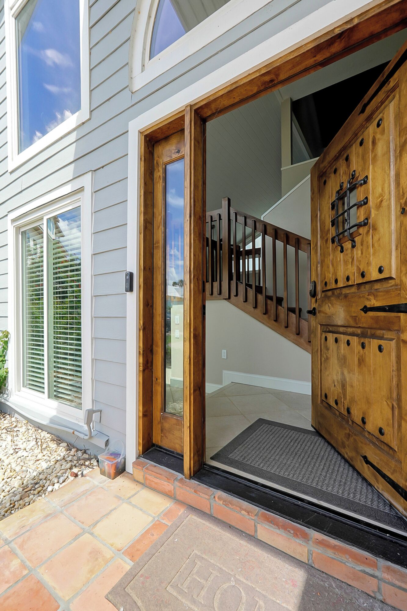 A house entrance with a wooden door, a glass door, and a staircase leading inside.