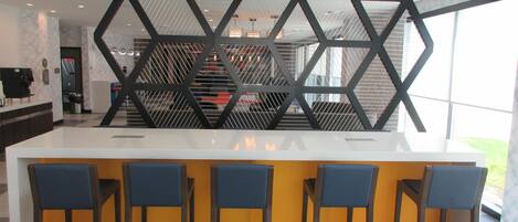 Una cocina moderna con una isla central, taburetes de bar y un revestimiento de pared decorativo geométrico.